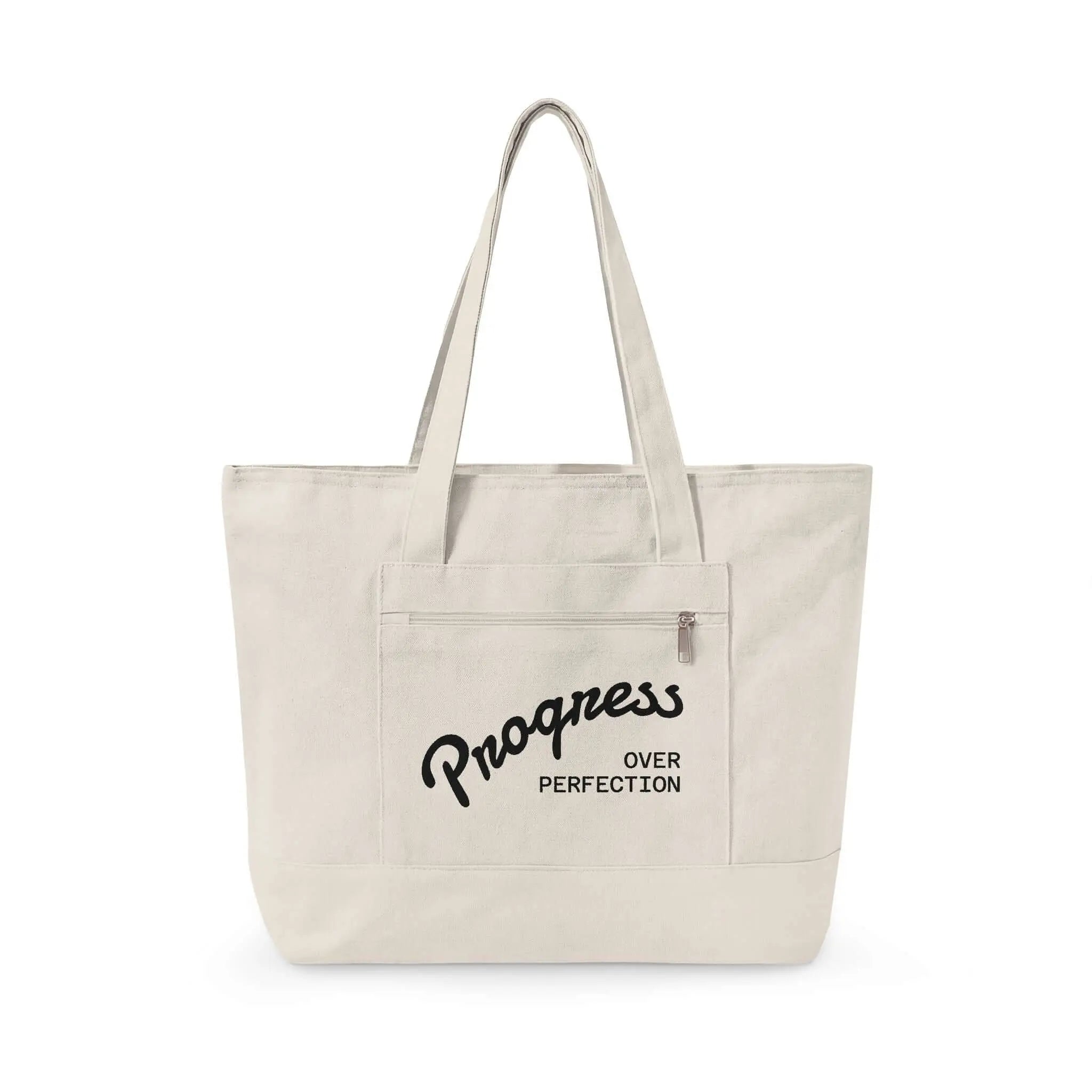 Progress Over Perfection Tote Bag | Minimalist canvas tote bag with black straps and zipper pocket featuring the motivational quote “Progress Over Perfection” in bold black typography on a neutral cream background.
