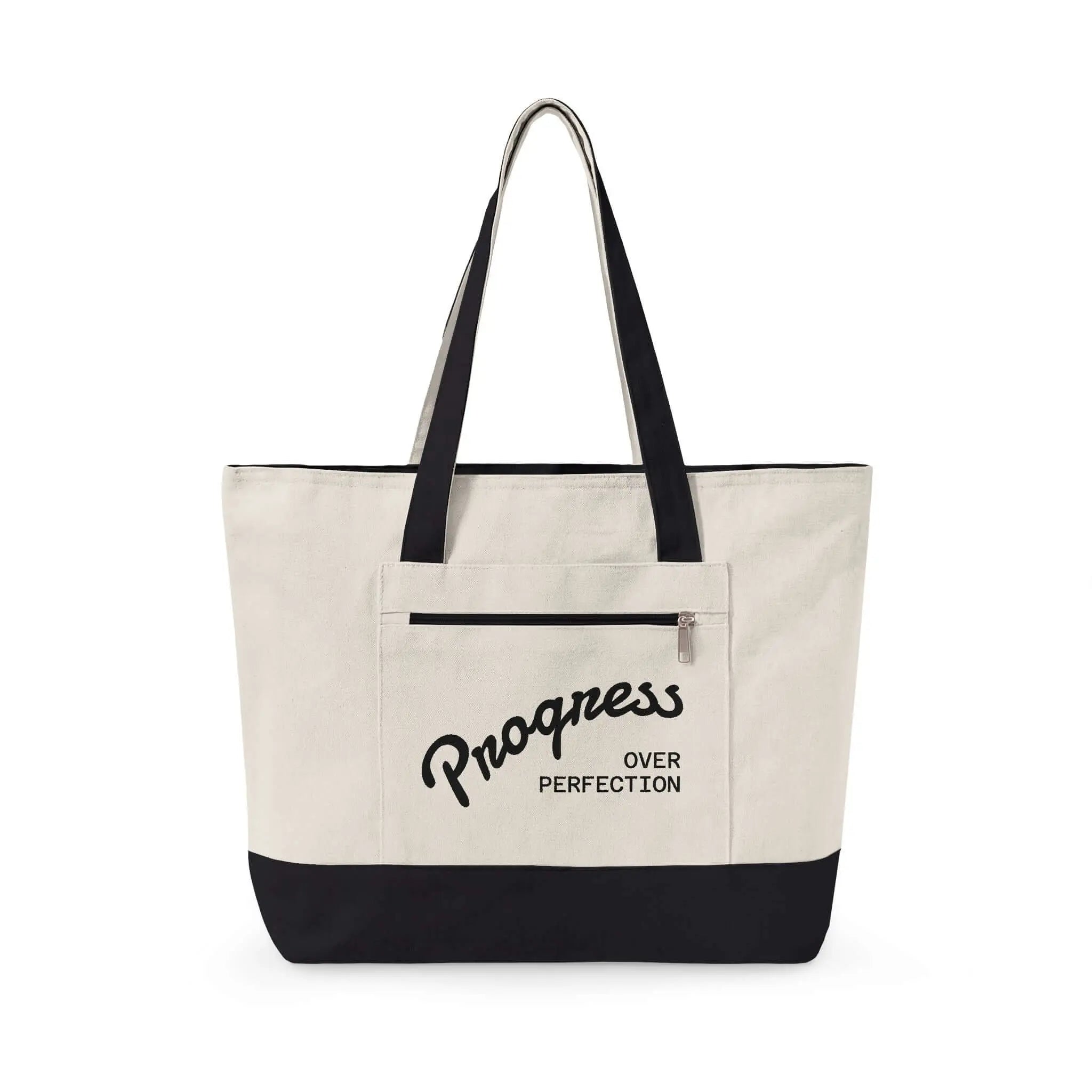Progress Over Perfection Tote Bag | Minimalist canvas tote bag with black straps and zipper pocket featuring the motivational quote “Progress Over Perfection” in bold black typography on a neutral cream background.